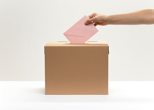 Umschlag wird in eine Wahlurne gesteckt