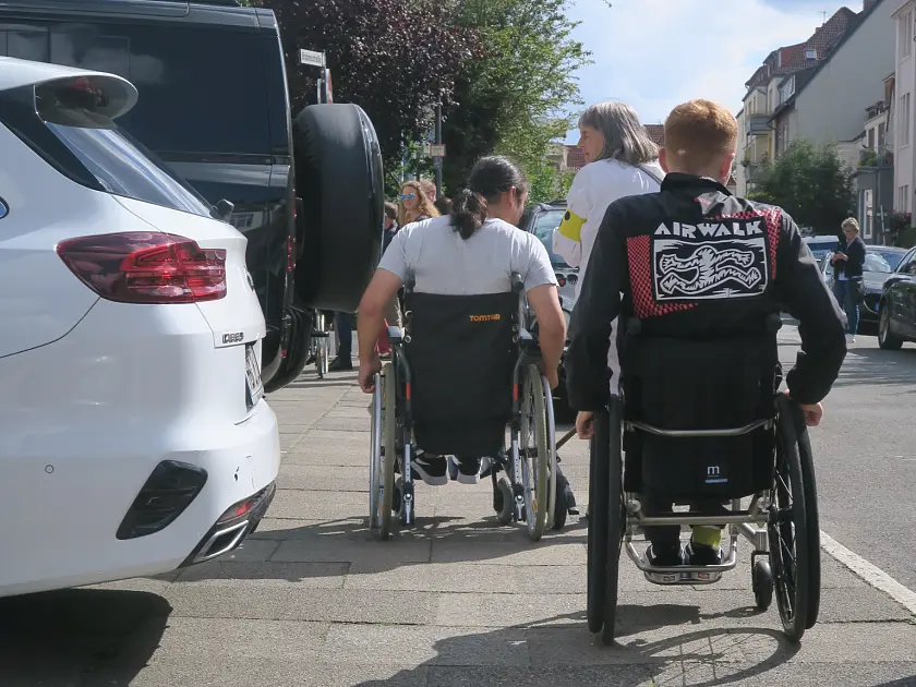 2 Personen im Rollstuhl von Hinten  